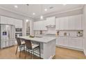 Modern kitchen with white cabinets, stainless steel appliances, large island with seating and hardwood floors at 2630 Timler Trce, Snellville, GA 30078