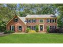 Classic brick home with a lush green lawn, mature trees, and manicured landscaping at 3267 Remembrance Trce, Lawrenceville, GA 30044
