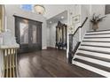 Elegant foyer with dark wood floors, soaring ceilings, stairs, and a designer front door with sidelights at 1250 Atherton Park, Roswell, GA 30076