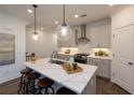 Contemporary kitchen features a large island with seating, pendant lights and stainless appliances at 1005 Crown Oak St # 44, Johns Creek, GA 30022