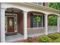 Inviting front porch with brickwork, white columns, and a decorative wood front door at 2525 Millwater Xing, Dacula, GA 30019