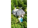 Aerial view of an expansive home featuring a pool and a lush green yard surrounded by trees at 9005 Old Southwick Pass, Alpharetta, GA 30022