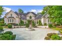 Daytime view of a charming two-story home with lush landscaping and a circular driveway with fountain at 9005 Old Southwick Pass, Alpharetta, GA 30022