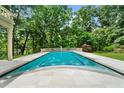 A rectangular swimming pool is surrounded by a tile patio and lush greenery creating a private backyard oasis at 9005 Old Southwick Pass, Alpharetta, GA 30022