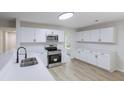 Modern kitchen with white cabinets, stainless steel appliances, and light wood-look flooring at 450 Pinevale Ct, Atlanta, GA 30349