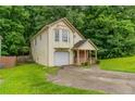 Inviting two-story home with attached garage and covered porch, set amidst mature trees and green lawn at 847 Ashley Ln, Stone Mountain, GA 30087