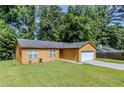 Charming single-story home with a two-car garage, manicured lawn, and a tree-lined backdrop at 9119 Woodgreen Way, Jonesboro, GA 30238