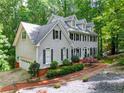 View of home showcasing two-car garage, brick foundation, and mature landscaping in a serene wooded setting at 120 Majesty Ln, Fayetteville, GA 30215