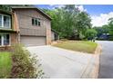 View of the home's exterior, including a driveway, a green lawn, and mature trees at 225 Lakeview W Rdg, Roswell, GA 30076