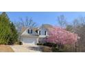 Two-story home boasts a well-manicured lawn, a tree with pink blooms, and a classic American flag at 107 Sedgefield Overlook, Dallas, GA 30157