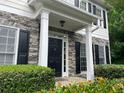 Close-up of the front entrance with stone accents, white columns, and black shutters adding classic charm at 107 Sedgefield Overlook, Dallas, GA 30157