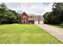 Charming red two-story home with a well-maintained lawn and a two-car attached garage at 1809 Brandi Ln, Loganville, GA 30052