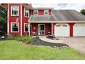 Charming two-story red home with a two car garage, features a quaint front porch at 1809 Brandi Ln, Loganville, GA 30052