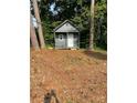 Small outdoor building with a gable roof nestled among mature trees in backyard at 354 Dublin Way, Lawrenceville, GA 30044