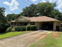 Traditional brick home featuring a lush green lawn, mature trees, and an attached carport at 1046 Waterside Se Dr, Conyers, GA 30013