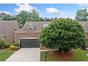 Lovely brick home showcasing a two-car garage, complemented by lush landscaping and mature trees at 123 Meridian Dr, Woodstock, GA 30188