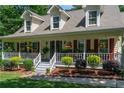 Inviting front porch adorned with hanging plants and decorative shrubs along the white picket railing, offering a cozy welcome at 2050 Lyda Ln, Loganville, GA 30052