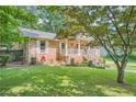 Charming brick home with manicured lawn and lush landscaping, and covered entryway and a mature tree at 3812 Chattawood Dr, Duluth, GA 30096