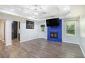 Bright living room featuring a blue brick fireplace, modern ceiling fan, and gray wood flooring at 225 Hardwood Dr, Covington, GA 30016