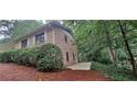 Brick exterior of a two-story home surrounded by lush greenery and a small concrete side yard at 2600 Amberly Dr, Dunwoody, GA 30360