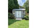 Well-maintained backyard shed with windows and double doors, surrounded by greenery at 158 Delano Dr, Decatur, GA 30032