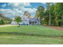 Expansive front lawn leads to a lovely home with mature trees, flowering bushes, and a welcoming front porch at 2980 Beards Rd, Buford, GA 30518