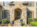 Close-up of home's stone entrance with arched doorway and blooming landscaping at 2517 Stone Manor Dr, Buford, GA 30519