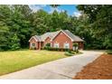 Brick home with driveway surrounded by lush trees, offering privacy and curb appeal at 3648 Clark Hill Way, Buford, GA 30519