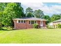 Single-story brick home with lush green lawn and mature trees creating a peaceful residential setting at 1167 Sanders Dr, Morrow, GA 30260