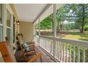 Relaxing front porch featuring rocking chairs, offering a tranquil outdoor space with views of the landscaped yard at 124 Hunters Mill Rd, Woodstock, GA 30188