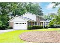 A two-story brick home with a large garage, lush landscaping, and an open front lawn at 5287 Vernon Lake Dr, Atlanta, GA 30338