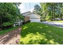 View of the property's two-car garage with an extra-long driveway on a sloping lawn at 5287 Vernon Lake Dr, Atlanta, GA 30338