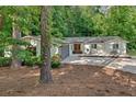Inviting single-story home with a gray garage, front patio seating area, manicured front yard and beautiful mature trees at 4492 Riverwood Cir, Decatur, GA 30035