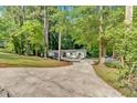 Scenic view of a quaint single-story home with an expansive driveway nestled among towering trees at 4492 Riverwood Cir, Decatur, GA 30035
