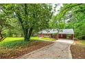 Scenic view of a brick home nestled among mature trees with a covered carport at 3080 Lynhurst Cir, Atlanta, GA 30311
