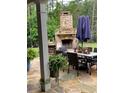 Stone outdoor fireplace on stone patio with an outdoor dining table and chairs at 203 Belmont Park Dr, Canton, GA 30115