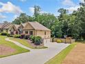 Wide driveway leading to a three-car garage, with manicured landscaping and basketball hoop at 212 Wilshire Ter, White, GA 30184
