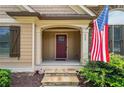 Close up of the front door entrance with stone steps, an American flag, and house number at 212 Wilshire Ter, White, GA 30184