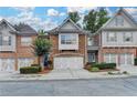 Charming brick townhome featuring a two-car garage, landscaped front yard, and inviting curb appeal at 5207 Merrimont Dr, Alpharetta, GA 30022