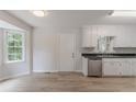 Eat-in kitchen featuring white cabinets, wood floor, stainless steel dishwasher, and natural light at 19 Willowbrook Ct, Acworth, GA 30101