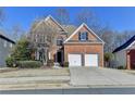 Inviting two-story brick home with attached two-car garage, complemented by a well-manicured lawn and shrubbery at 1924 Wilkenson Xing, Marietta, GA 30066