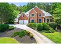 Elegant brick home with two-car garage, surrounded by mature trees and manicured landscaping at 542 Fairway Dr, Woodstock, GA 30189