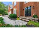 Elegant brick home entrance featuring a stone pathway, a set of black double doors, and lush landscaping at 542 Fairway Dr, Woodstock, GA 30189
