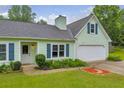 Close-up of a light green home with blue shutters, an attached garage, and manicured landscaping at 1789 Brandi Ln, Loganville, GA 30052