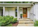 A close-up view of the house's front door, showcasing its warm wood design, sidelight windows, and stone entryway at 80 Maryeanna Dr, Sandy Springs, GA 30342