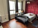 Bright bedroom featuring hardwood floors, large windows, and a unique red paneled accent wall at 20 Marietta Nw St # 13C, Atlanta, GA 30303