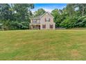 Traditional home set on a sprawling green lawn surrounded by mature trees and well manicured landscaping at 6350 Summer Pl, Douglasville, GA 30135