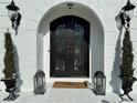 Detailed view of the arched front door with ironwork, lanterns, and manicured greenery at 3011 Flat Shoals Sw Rd, Conyers, GA 30094
