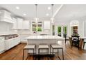 Modern, all-white kitchen featuring a large center island, pendant lighting, stainless steel appliances, and hardwood flooring at 3925 Sheldon Ne Dr, Atlanta, GA 30342