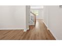 Bright hallway featuring wood-look floors, neutral paint, white trim, and an oak staircase with black iron balusters at 603 River Gardens Se Dr, Atlanta, GA 30354